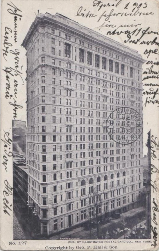 A black and white postcard of a tall pale stone office building on a corner, with handwritten notes in the margins and a 1903 postmark