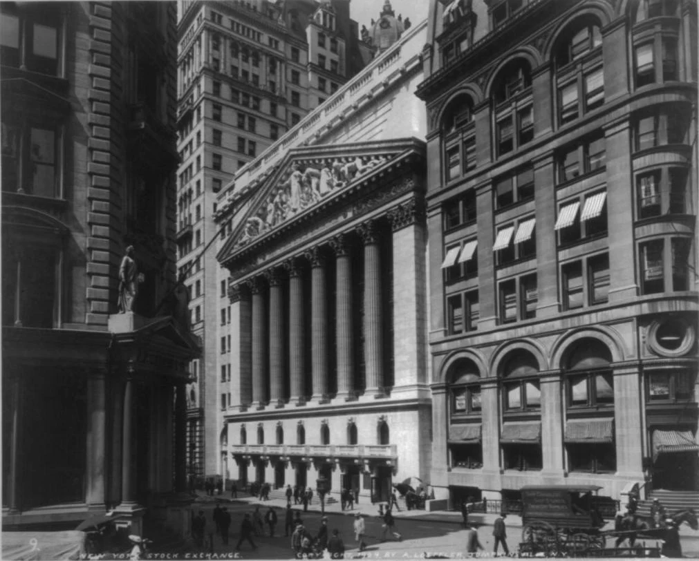 A black and white 1904 photo of the Stock Exchange&rsquo;s columned temple front on Broad Street, with pedestrians and a horse-drawn wagon on the street and a statue in the foreground