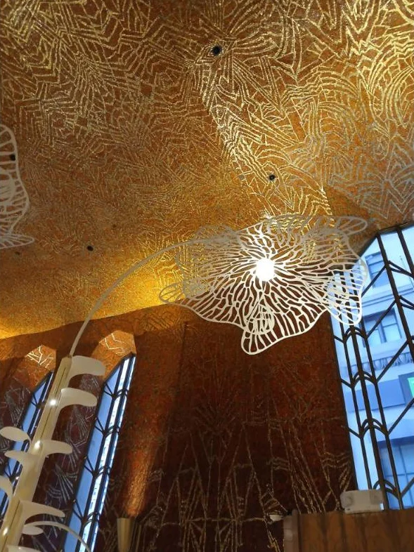 Close view of a gold and red mosaic ceiling with a white cut-metal light fixture