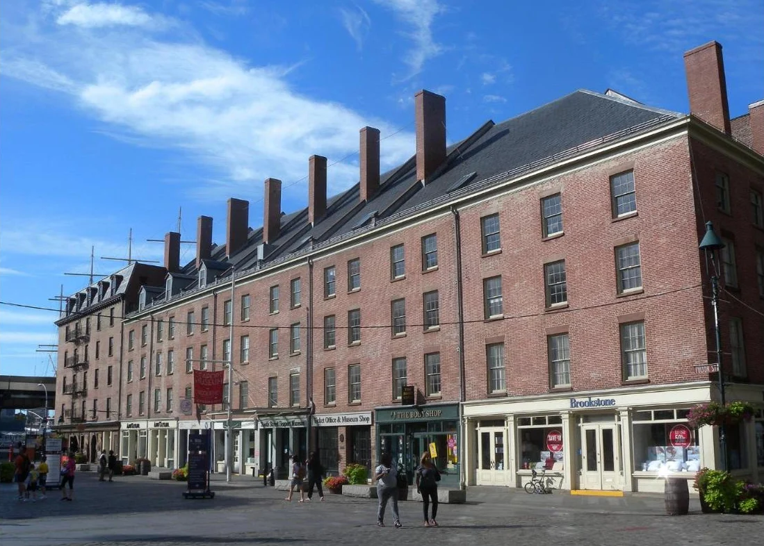 A long row of red brick Federal buildings with tall chimneys on a cobblestone plaza