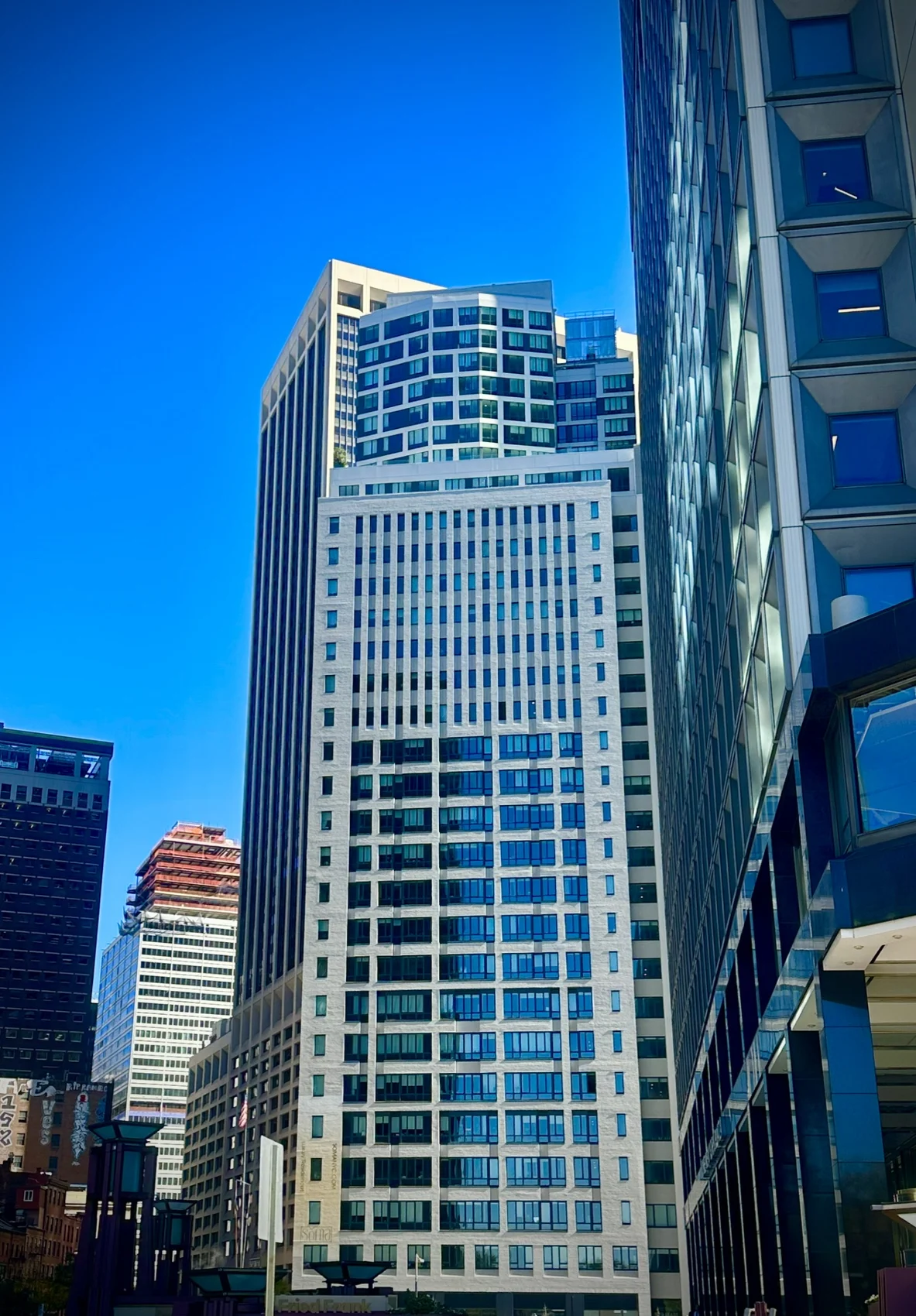A pale brick tower with a curved glass addition on top, the SoMA sign at its base, under a deep blue sky