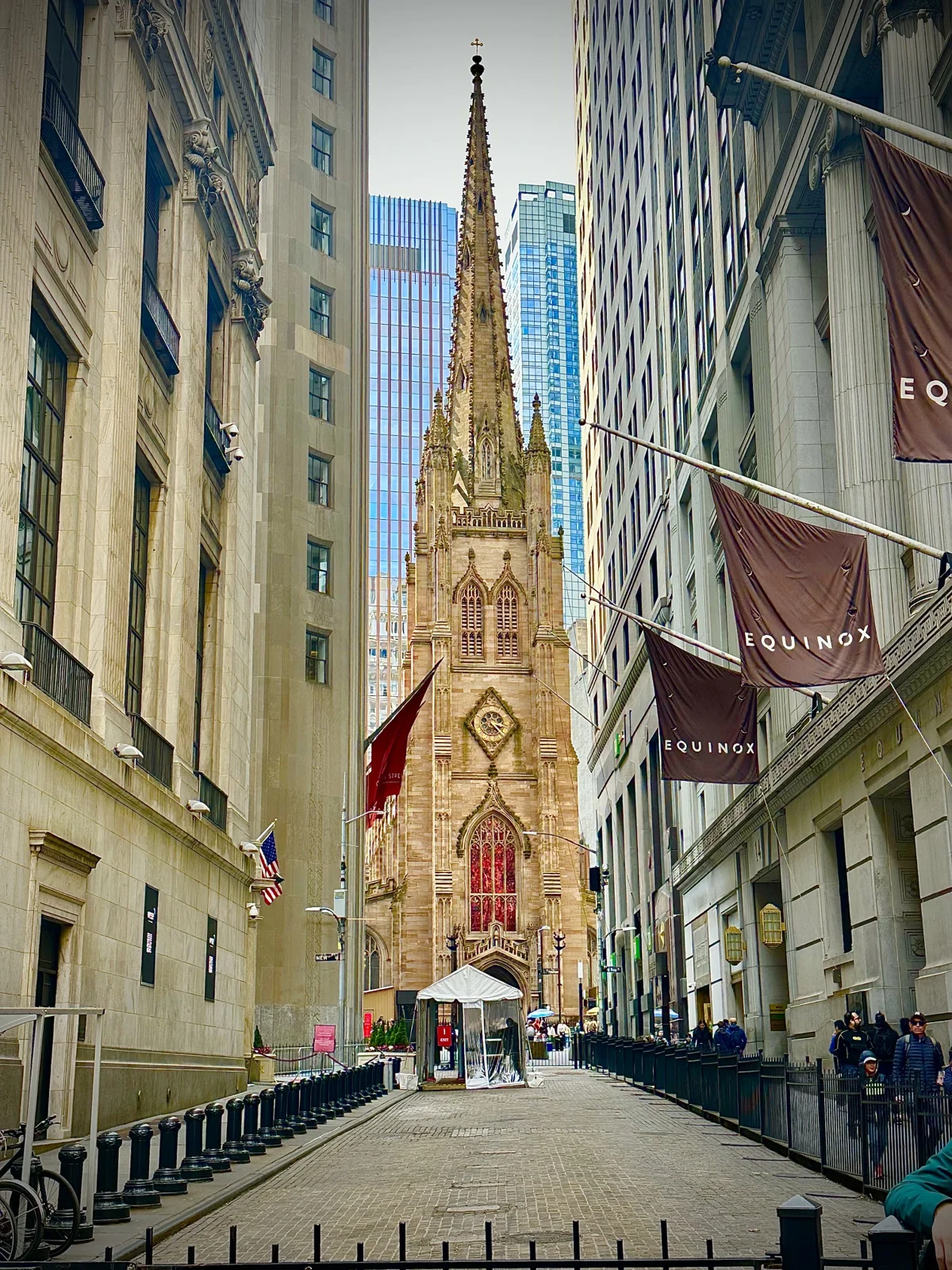 The Gothic Revival spire of Trinity Church rising at the end of Wall Street between stone office buildings