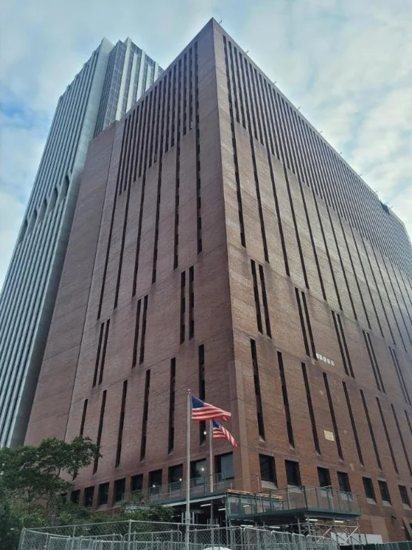 Looking up the brick face of 25 Water Street with American flags at the entrance