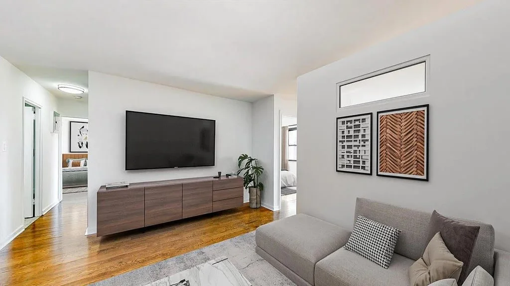 A living area with a low media console, a television and framed prints