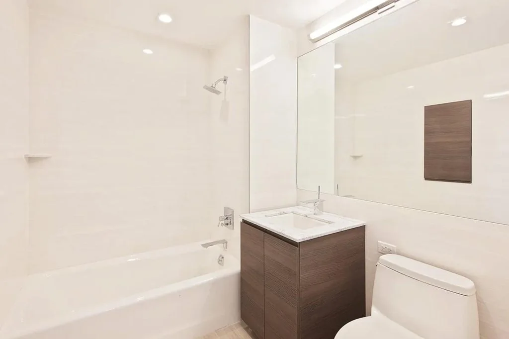 A bath with a deep tub, a wood vanity and a wide mirror