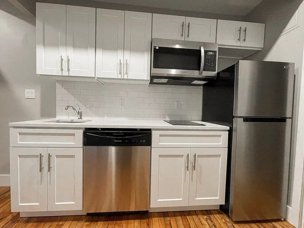 A white kitchen with shaker cabinets, a subway tile backsplash and stainless steel appliances