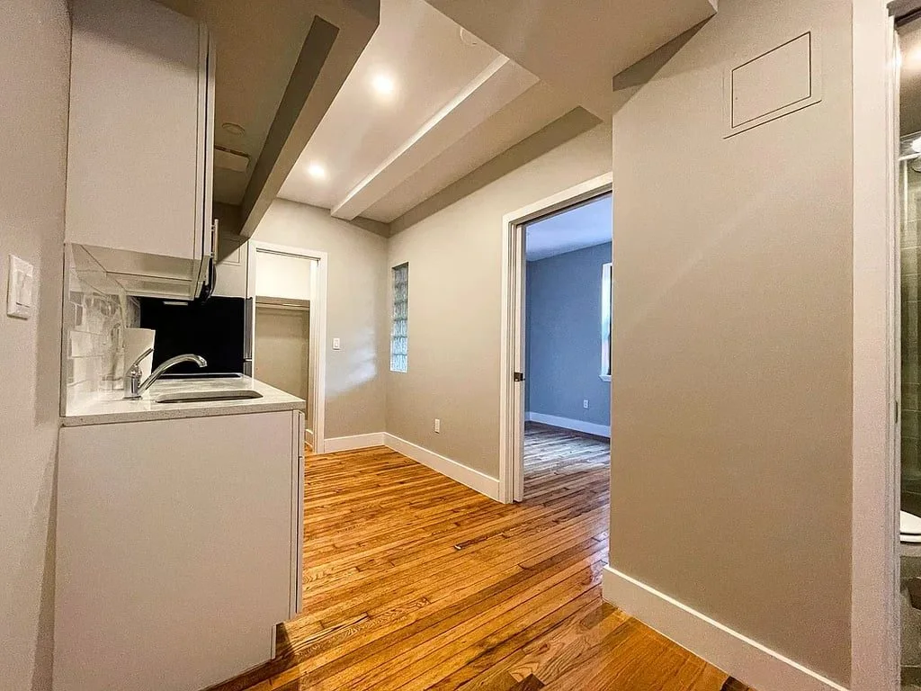 The kitchen opening onto a bright room with hardwood floors and a tall ceiling