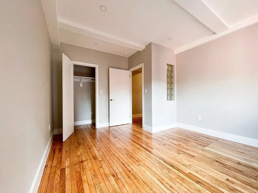 A bright room with a beamed ceiling, hardwood floors and a closet